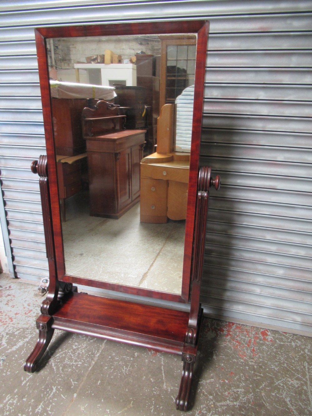 A 19th-century full-length mahogany cheval mirror featuring turned side adjustment handles, curved scroll legs, and a rectangular tilting glass frame. View X