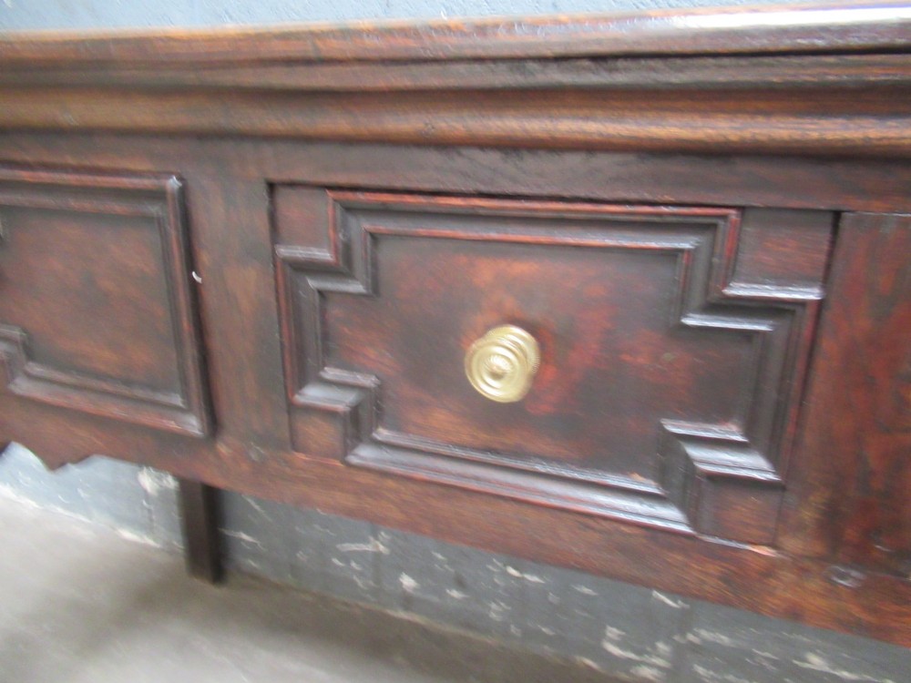 An antique dark oak dresser base featuring three drawers with geometric mouldings and brass knobs, supported by cabriole legs. View V