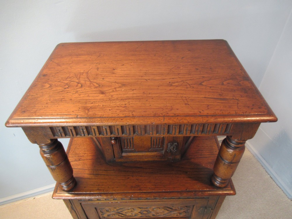 A small carved dark oak court cupboard featuring a two-tiered structure with turned bulbous supports and carved panel doors. View IV