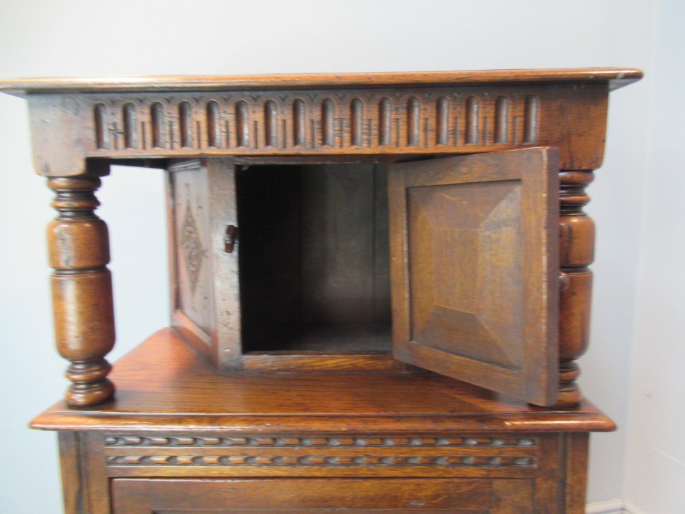 A small carved dark oak court cupboard featuring a two-tiered structure with turned bulbous supports and carved panel doors. View VIII