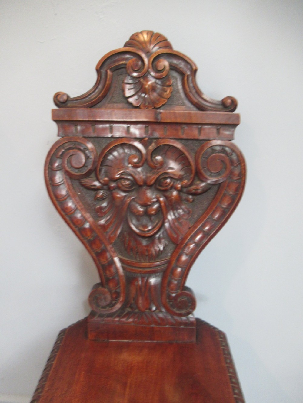 A Victorian carved mahogany hall chair featuring a detailed lion head mask sculpted into the backrest and a solid timber seat. View IV