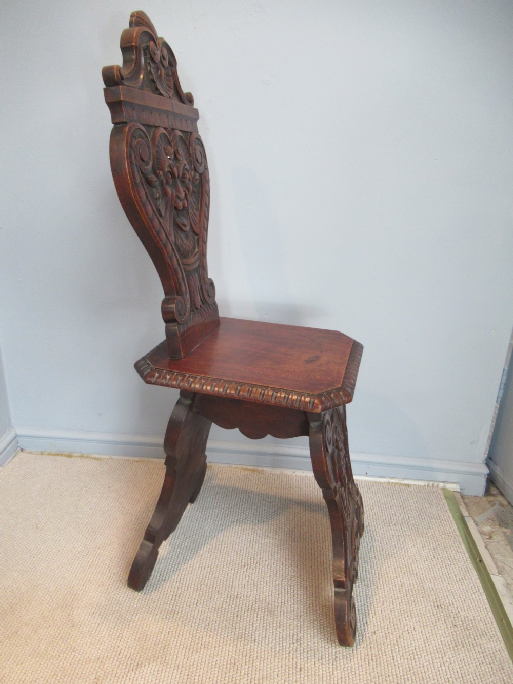 A Victorian carved mahogany hall chair featuring a detailed lion head mask sculpted into the backrest and a solid timber seat. View V