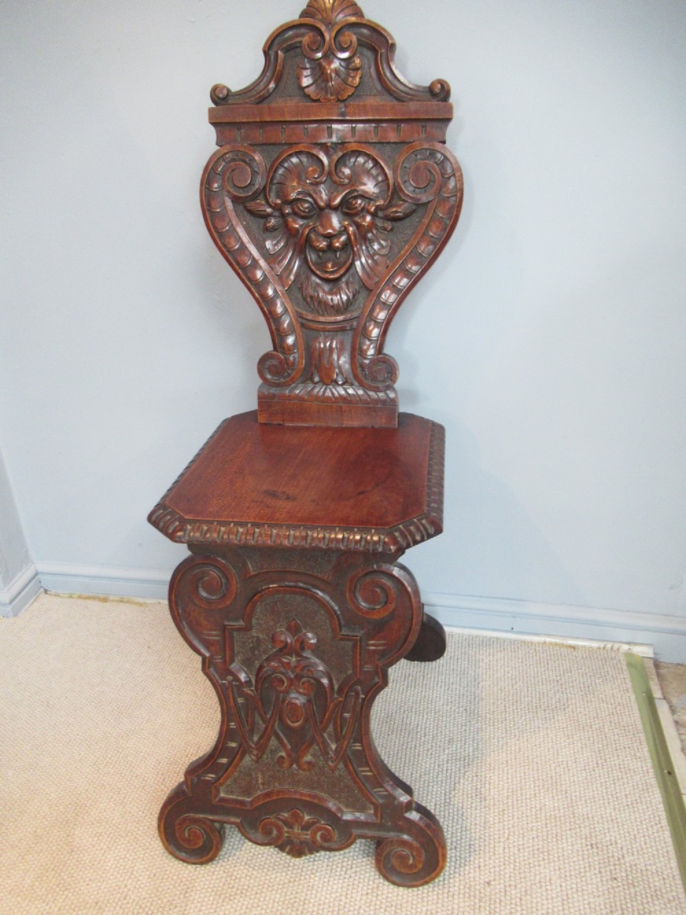 A Victorian carved mahogany hall chair featuring a detailed lion head mask sculpted into the backrest and a solid timber seat. View VIII