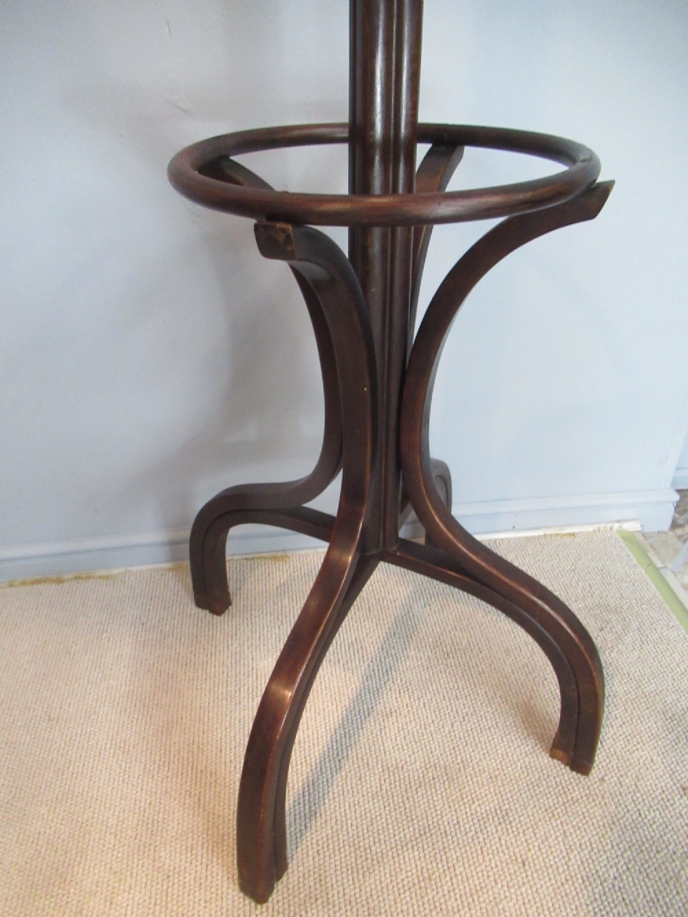 A dark brown bentwood hat and coat stand with upper curved hooks, a turned central stem, a lower umbrella ring, and four splayed feet. View IV