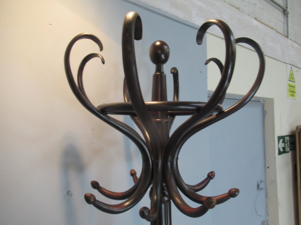 A dark brown bentwood hat and coat stand with upper curved hooks, a turned central stem, a lower umbrella ring, and four splayed feet. View V