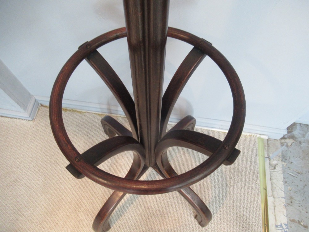 A dark brown bentwood hat and coat stand with upper curved hooks, a turned central stem, a lower umbrella ring, and four splayed feet. View VII
