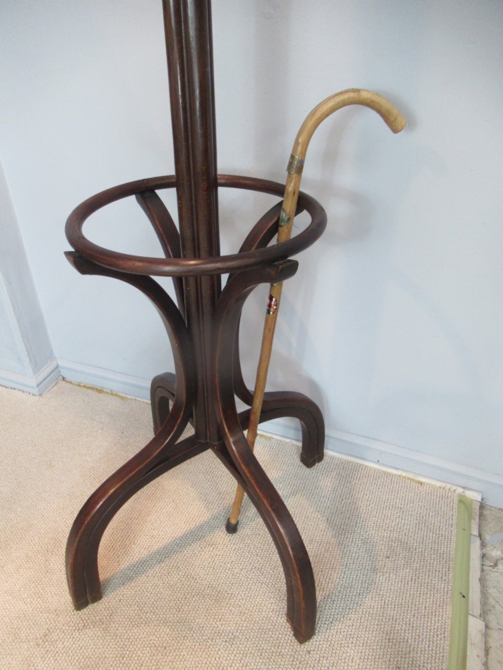A dark brown bentwood hat and coat stand with upper curved hooks, a turned central stem, a lower umbrella ring, and four splayed feet. View VIII