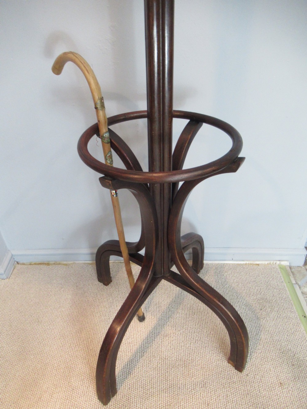 A dark brown bentwood hat and coat stand with upper curved hooks, a turned central stem, a lower umbrella ring, and four splayed feet. View IX