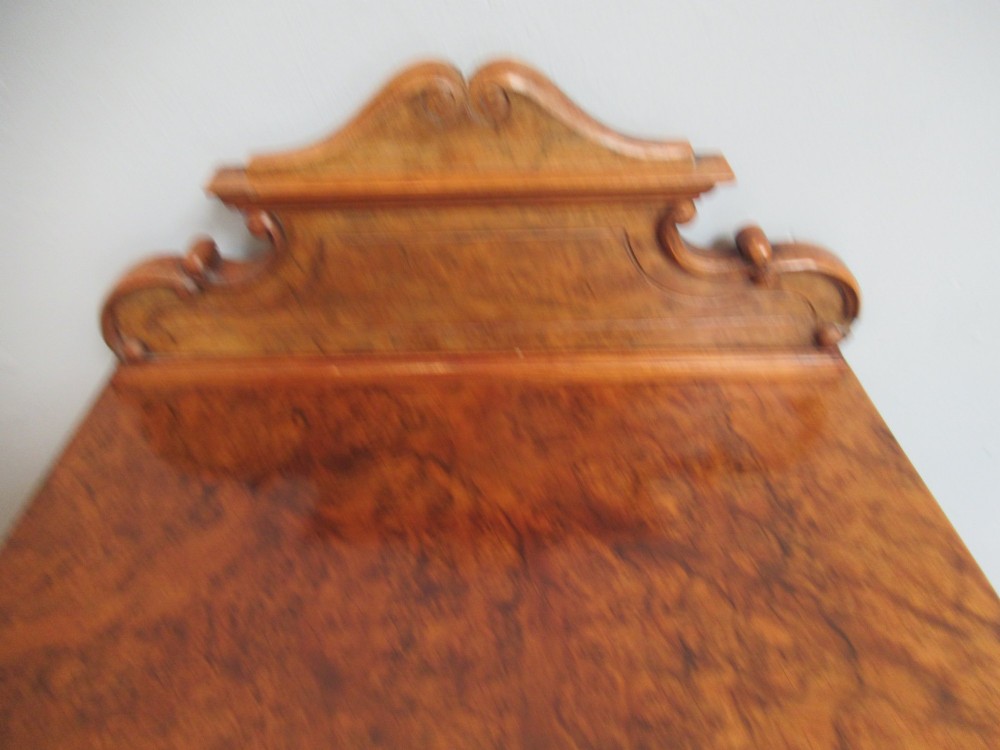 A late Victorian burr walnut bedside cabinet featuring a single panelled door with a brass drop handle, a shaped pediment gallery, and a plinth base on bun feet. View III