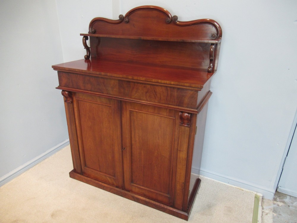 A Victorian mahogany chiffonier with a raised gallery shelf supported by carved scrolls above a two-door cabinet on a solid plinth base. View II