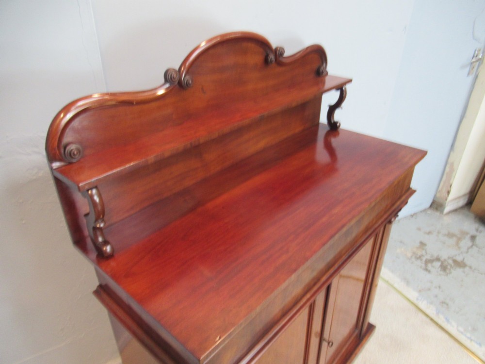A Victorian mahogany chiffonier with a raised gallery shelf supported by carved scrolls above a two-door cabinet on a solid plinth base. View IV