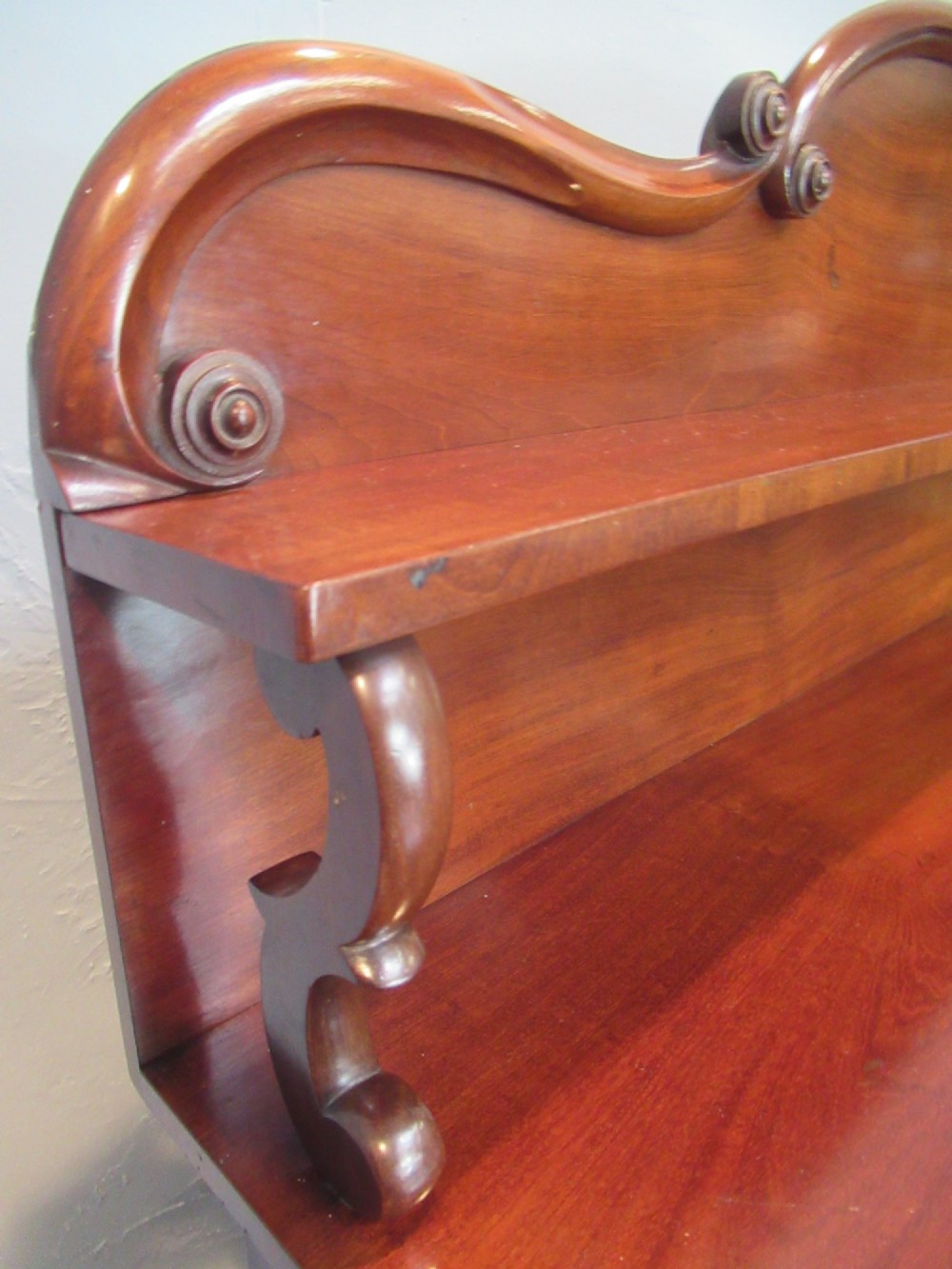 A Victorian mahogany chiffonier with a raised gallery shelf supported by carved scrolls above a two-door cabinet on a solid plinth base. View V