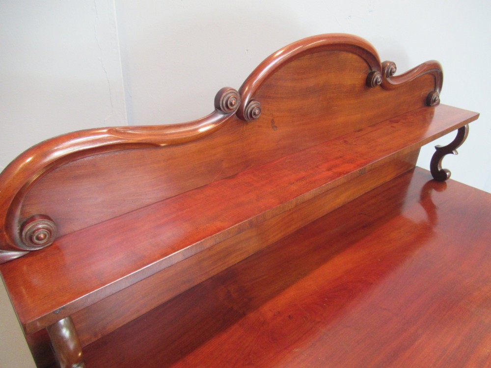 A Victorian mahogany chiffonier with a raised gallery shelf supported by carved scrolls above a two-door cabinet on a solid plinth base. View VI