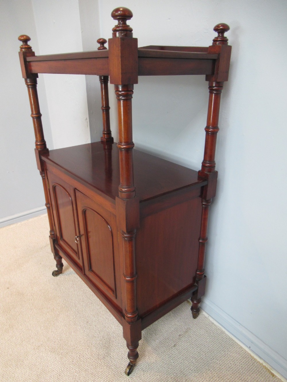 A Victorian mahogany chiffonier cabinet featuring a raised top tier supported by turned pillars above a two-door lower cupboard on brass castors. View III