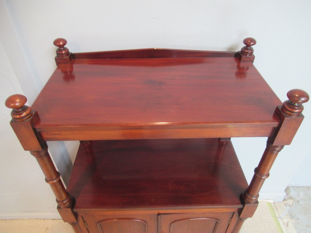 A Victorian mahogany chiffonier cabinet featuring a raised top tier supported by turned pillars above a two-door lower cupboard on brass castors. View V