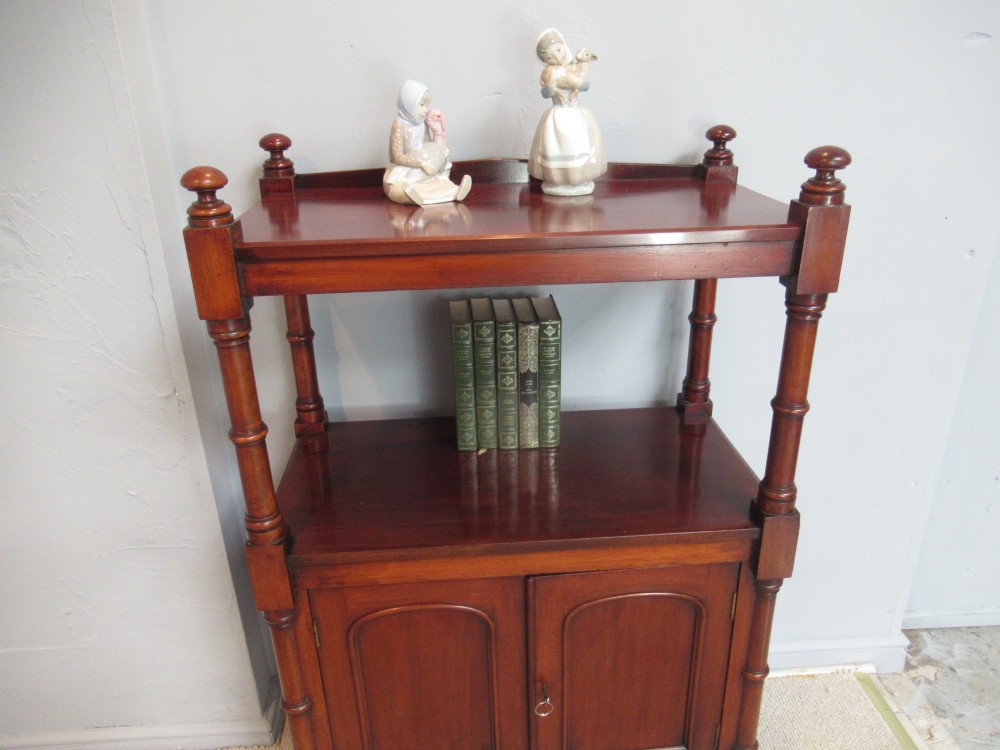 A Victorian mahogany chiffonier cabinet featuring a raised top tier supported by turned pillars above a two-door lower cupboard on brass castors. View VII