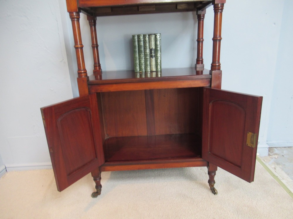 A Victorian mahogany chiffonier cabinet featuring a raised top tier supported by turned pillars above a two-door lower cupboard on brass castors. View VIII