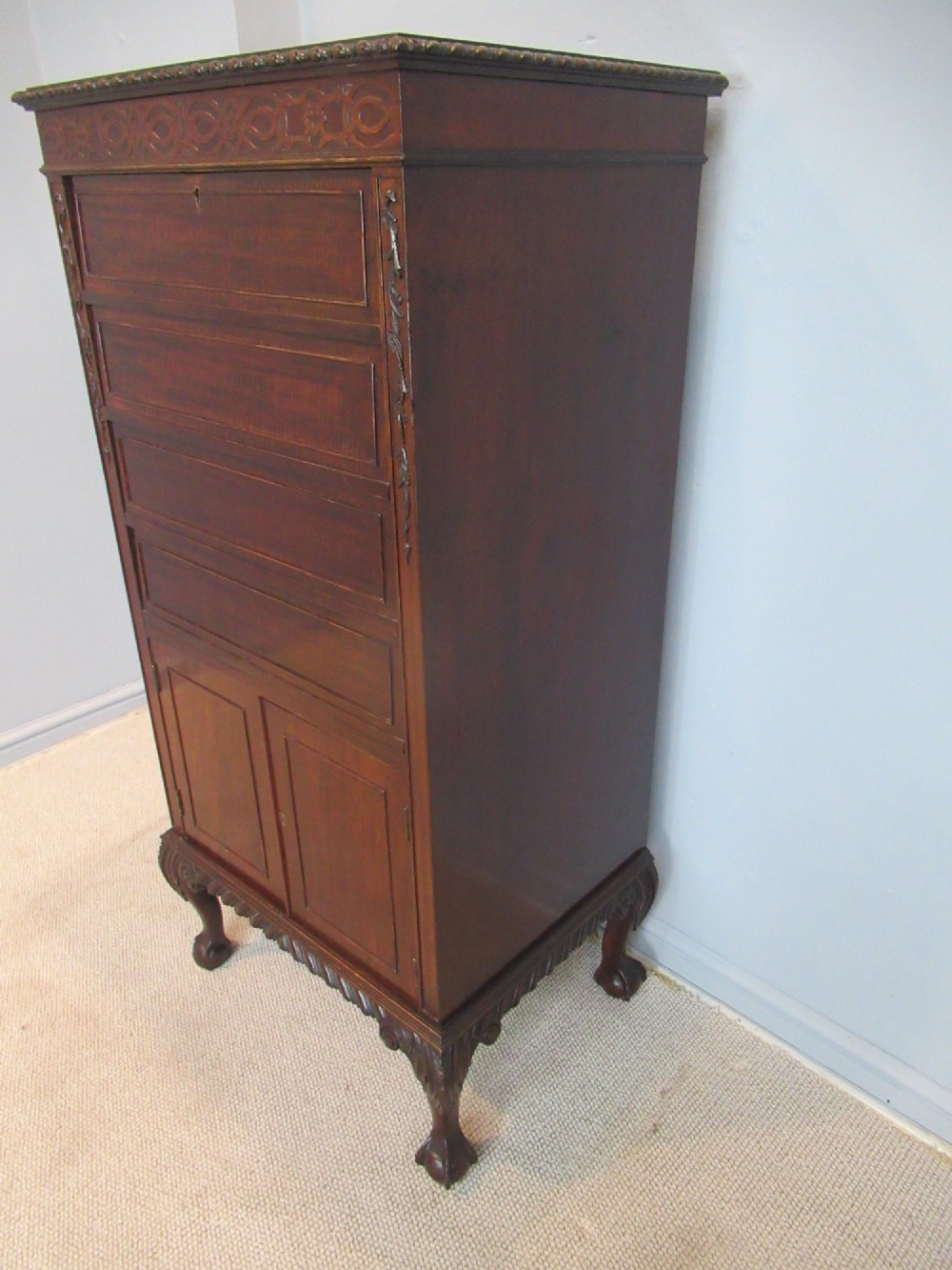 A tall, narrow dark mahogany music cabinet featuring fall-front drawer compartments, carved geometric fretwork, and cabriole legs ending in ball-and-claw feet. View II