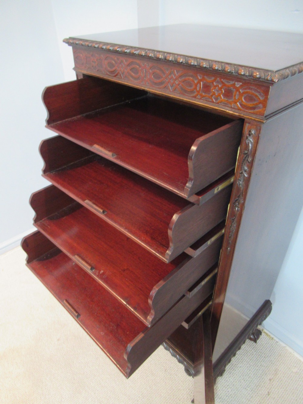 A tall, narrow dark mahogany music cabinet featuring fall-front drawer compartments, carved geometric fretwork, and cabriole legs ending in ball-and-claw feet. View VIII