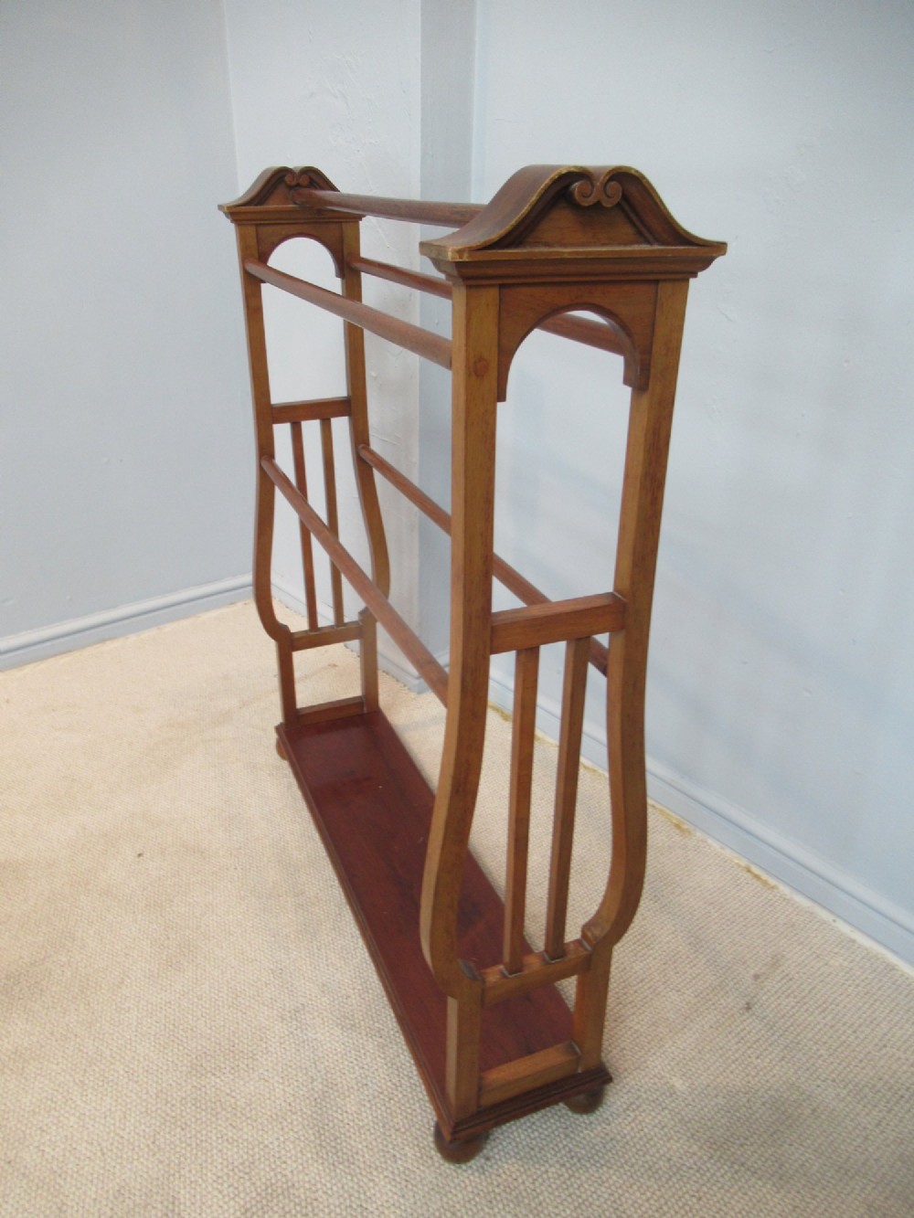 A freestanding Victorian walnut towel rail featuring carved end supports, curved pediment top caps, multiple horizontal wooden rungs, and a flat lower shelf. View VI
