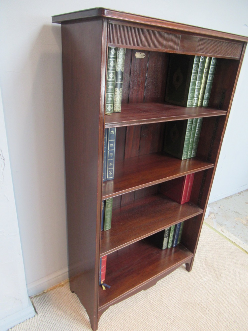 An antique dark mahogany open bookcase featuring four adjustable shelves, fluted frieze detailing at the top, and bracket feet. View III