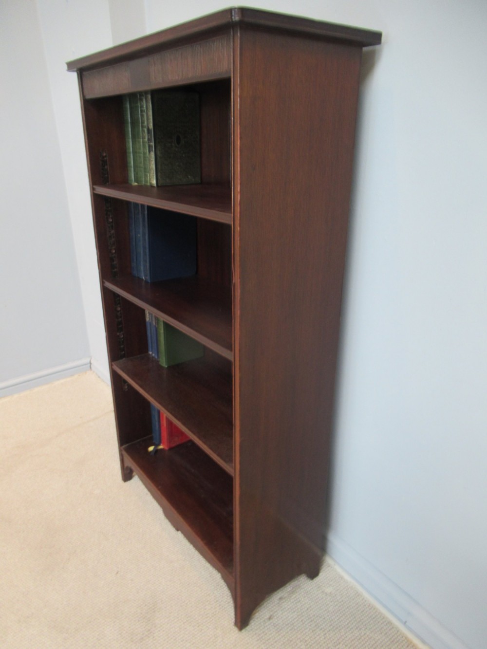 An antique dark mahogany open bookcase featuring four adjustable shelves, fluted frieze detailing at the top, and bracket feet. View V