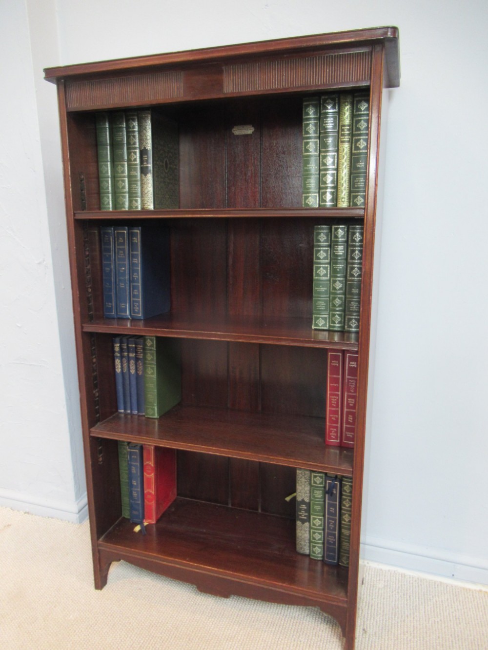 An antique dark mahogany open bookcase featuring four adjustable shelves, fluted frieze detailing at the top, and bracket feet. View VIII