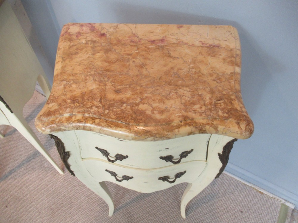 A pair of cream painted French style bedside cabinets featuring variegated marble tops, two drawers with brass handles, and slender cabriole legs. View II