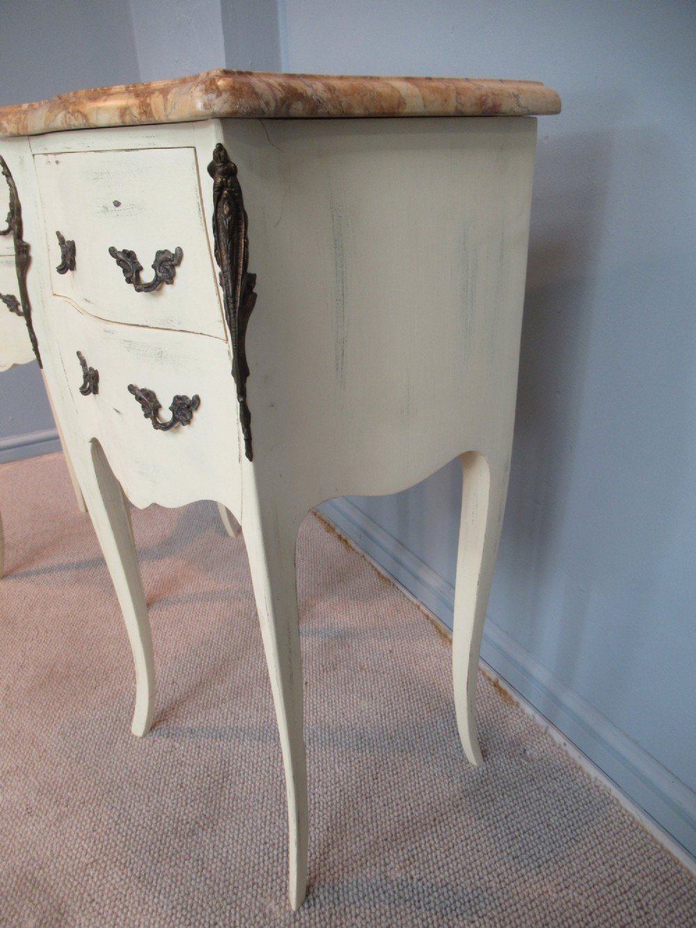 A pair of cream painted French style bedside cabinets featuring variegated marble tops, two drawers with brass handles, and slender cabriole legs. View IV