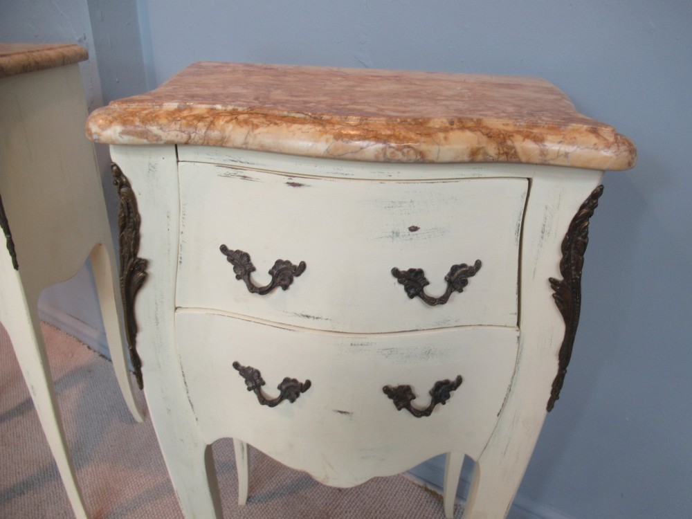 A pair of cream painted French style bedside cabinets featuring variegated marble tops, two drawers with brass handles, and slender cabriole legs. View VI