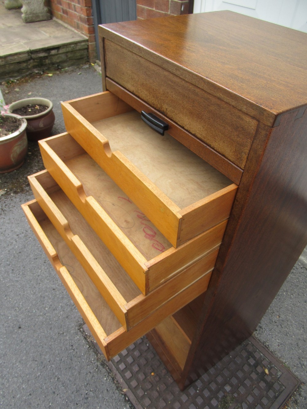 A tall, vertical mahogany filing cabinet with a closed flexible slat tambour front door and a dark handle at the bottom base. View VIII