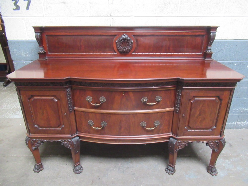 An Edwardian carved mahogany sideboard featuring a raised backboard with a carved shell motif, central bow-front drawers, side cupboard doors, and cabriole legs with ball and claw feet. View II