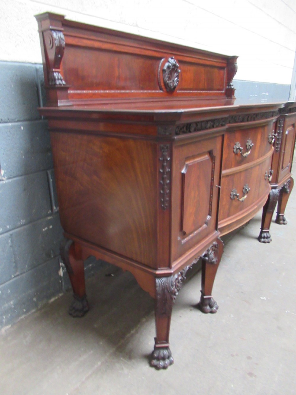 An Edwardian carved mahogany sideboard featuring a raised backboard with a carved shell motif, central bow-front drawers, side cupboard doors, and cabriole legs with ball and claw feet. View III