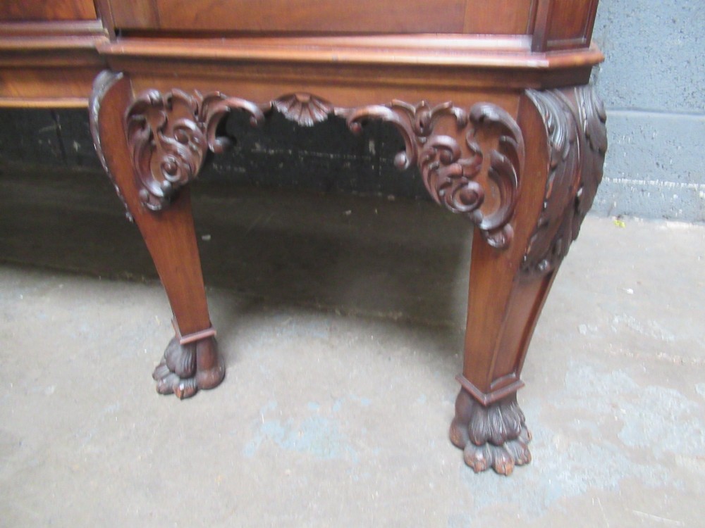 An Edwardian carved mahogany sideboard featuring a raised backboard with a carved shell motif, central bow-front drawers, side cupboard doors, and cabriole legs with ball and claw feet. View V