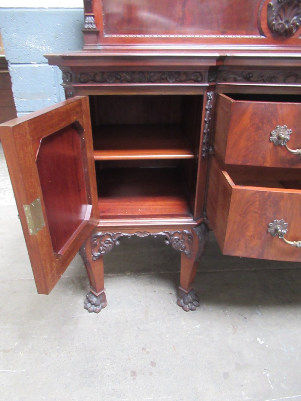 An Edwardian carved mahogany sideboard featuring a raised backboard with a carved shell motif, central bow-front drawers, side cupboard doors, and cabriole legs with ball and claw feet. View X