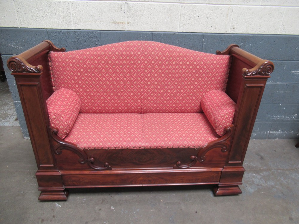 A 19th-century mahogany upholstered bench featuring scrolled armrests, flame mahogany veneered panelling, and red patterned fabric seating with bolster cushions. View II
