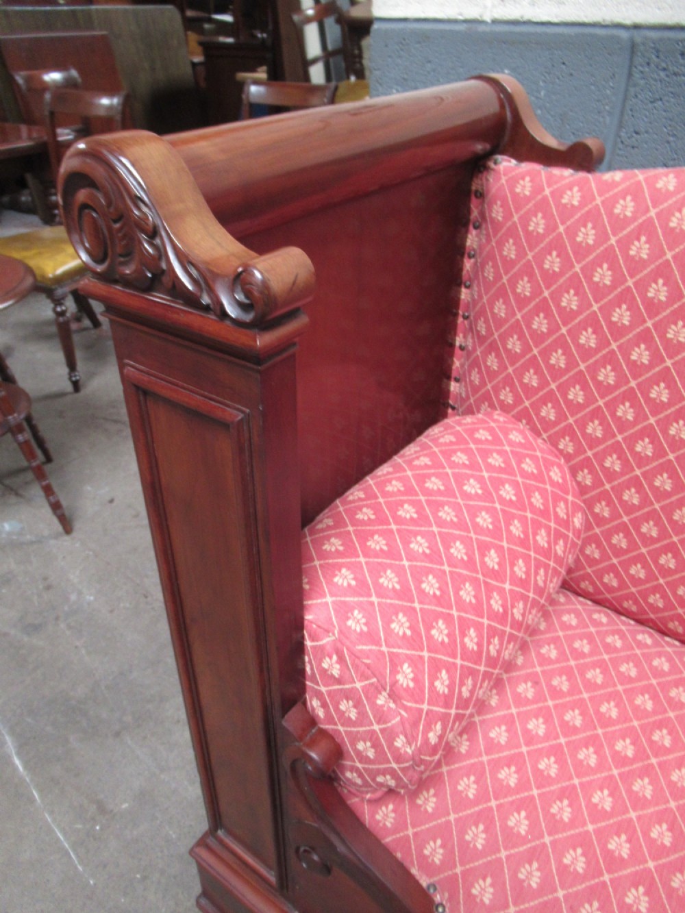 A 19th-century mahogany upholstered bench featuring scrolled armrests, flame mahogany veneered panelling, and red patterned fabric seating with bolster cushions. View VII