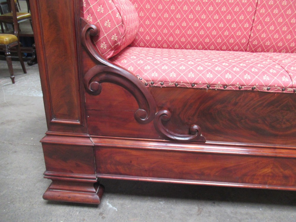 A 19th-century mahogany upholstered bench featuring scrolled armrests, flame mahogany veneered panelling, and red patterned fabric seating with bolster cushions. View VIII