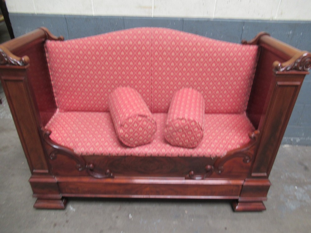 A 19th-century mahogany upholstered bench featuring scrolled armrests, flame mahogany veneered panelling, and red patterned fabric seating with bolster cushions. View XII