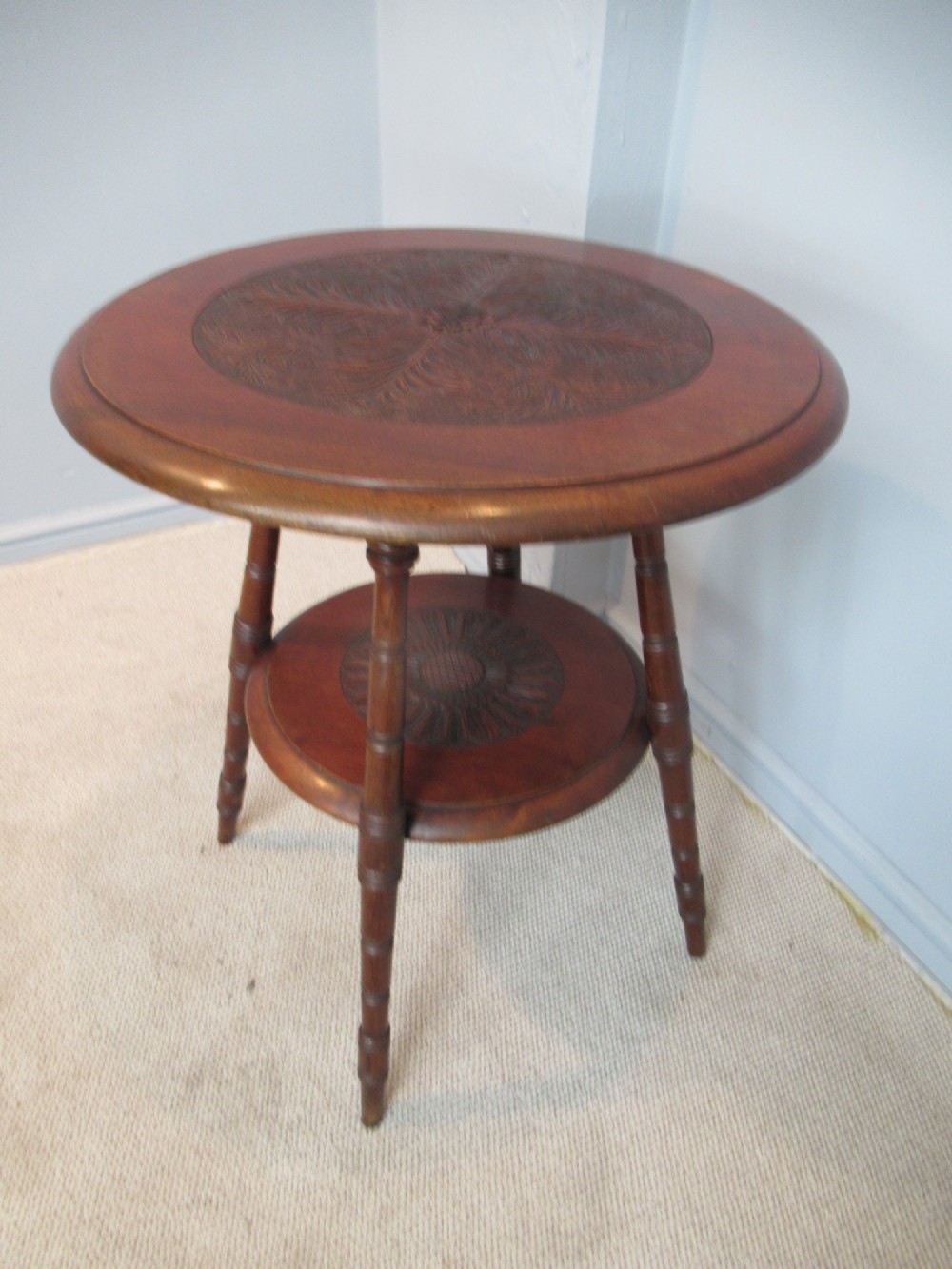 A round Victorian mahogany side table featuring a carved top, turned spindle legs, and a lower carved shelf. View II