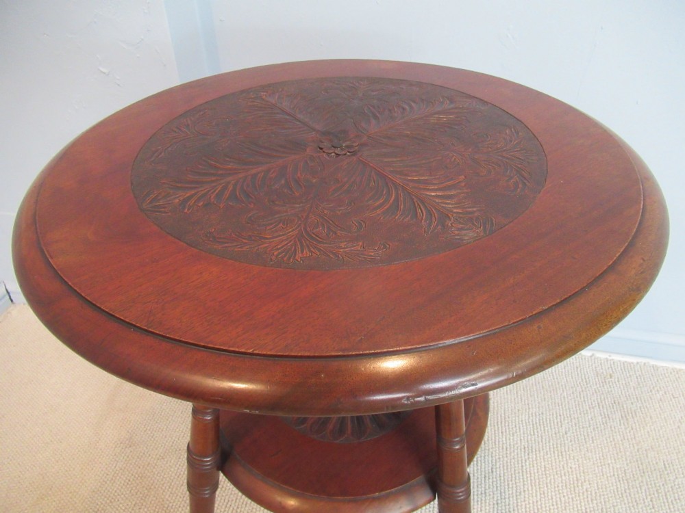 A round Victorian mahogany side table featuring a carved top, turned spindle legs, and a lower carved shelf. View IV