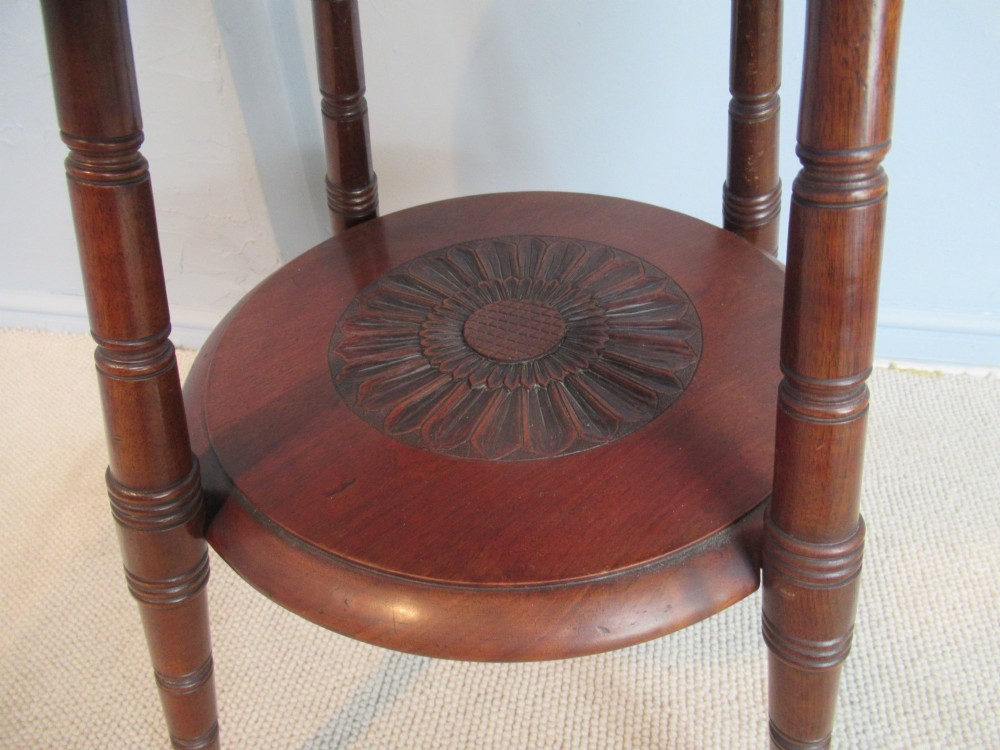 A round Victorian mahogany side table featuring a carved top, turned spindle legs, and a lower carved shelf. View V