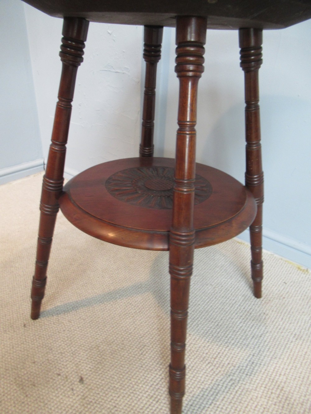 A round Victorian mahogany side table featuring a carved top, turned spindle legs, and a lower carved shelf. View VI