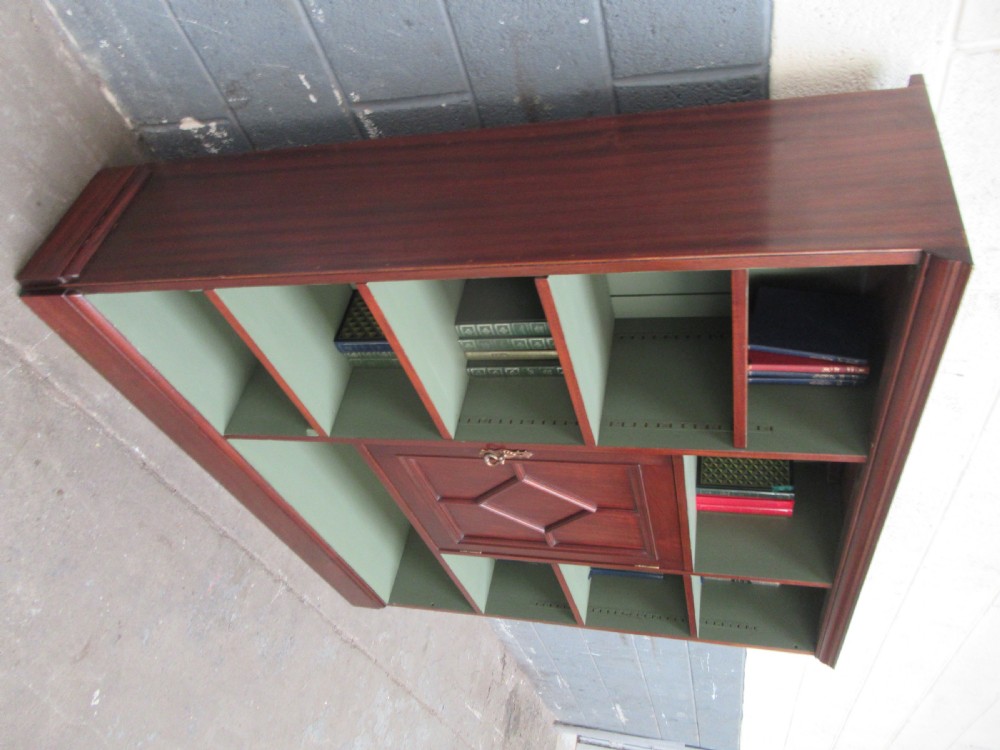 An Edwardian mahogany open bookcase with asymmetrical sage green painted shelves and a central panelled cupboard door featuring diamond moulding. View III