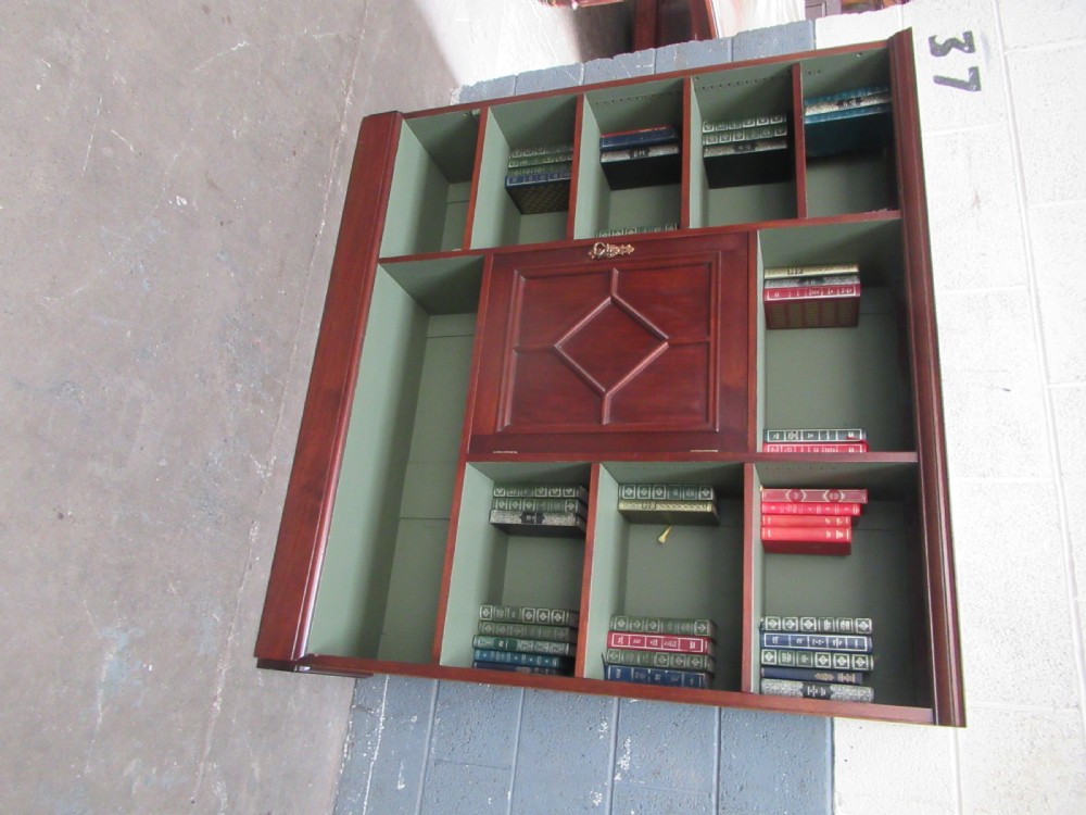 An Edwardian mahogany open bookcase with asymmetrical sage green painted shelves and a central panelled cupboard door featuring diamond moulding. View V