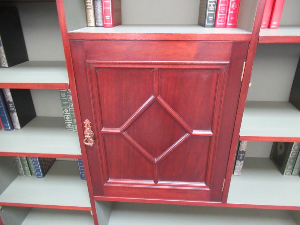 An Edwardian mahogany open bookcase with asymmetrical sage green painted shelves and a central panelled cupboard door featuring diamond moulding. View VIII