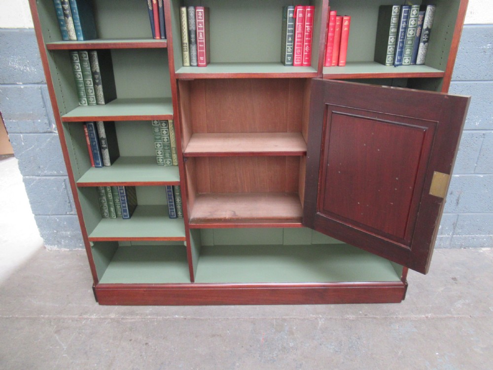 An Edwardian mahogany open bookcase with asymmetrical sage green painted shelves and a central panelled cupboard door featuring diamond moulding. View IX
