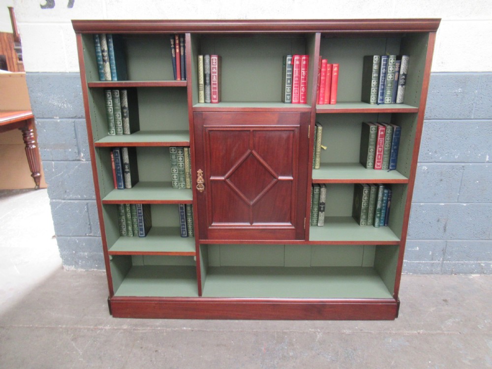 An Edwardian mahogany open bookcase with asymmetrical sage green painted shelves and a central panelled cupboard door featuring diamond moulding. View XI