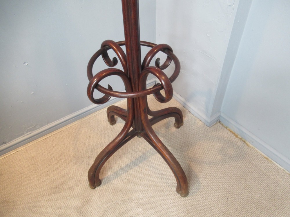 A dark brown bentwood hat and coat stand featuring multiple curved upper hooks, a central turned pole, a lower umbrella ring, and splayed legs. View III