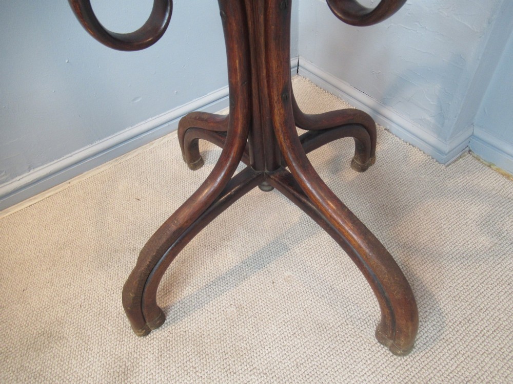 A dark brown bentwood hat and coat stand featuring multiple curved upper hooks, a central turned pole, a lower umbrella ring, and splayed legs. View IV